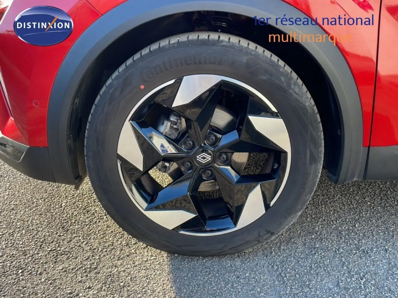 Gros plan sur la roue avant gauche du Renault Captur rouge Désir Métal avec jante noire et argentée au design géométrique.