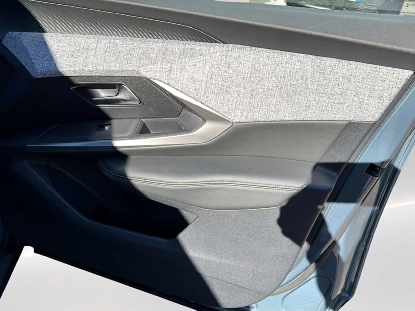 Vue rapprochée de la porte avant gauche bleu Ingara du Peugeot 3008 2025 avec garniture tissu et cuir noir.