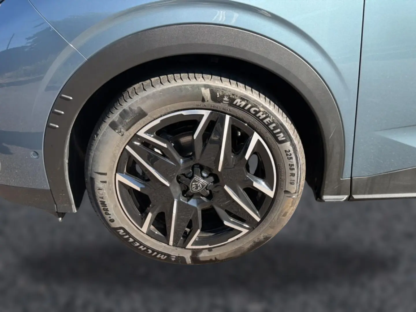 Gros plan sur la roue arrière droite bleu métallisé du Peugeot 3008 1.2 hybrid 145 allure avec jante alu noire et argentée.