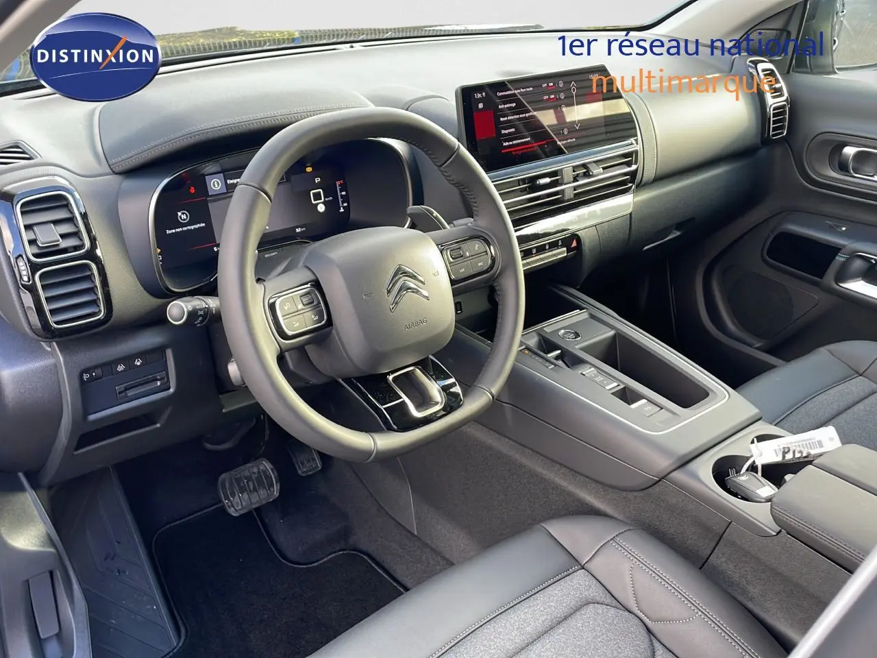 Intérieur de la Citroën C5 Aircross 2025, vue côté conducteur, tableau de bord moderne avec écran tactile et volant multifonction.