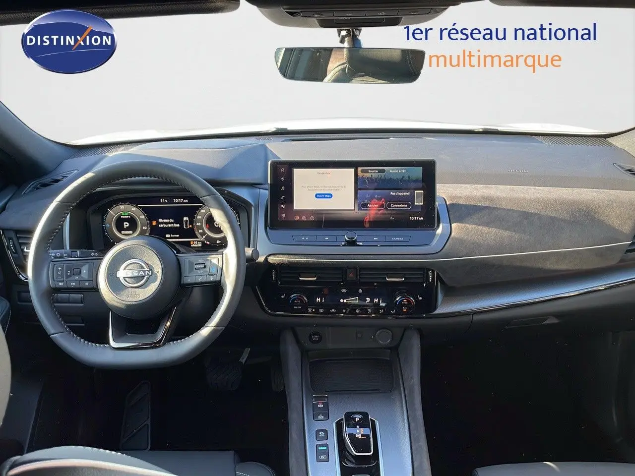 Vue intérieure du tableau de bord du Nissan Qashqai 2025 blanc nacré, avec écran tactile central et volant multifonction.