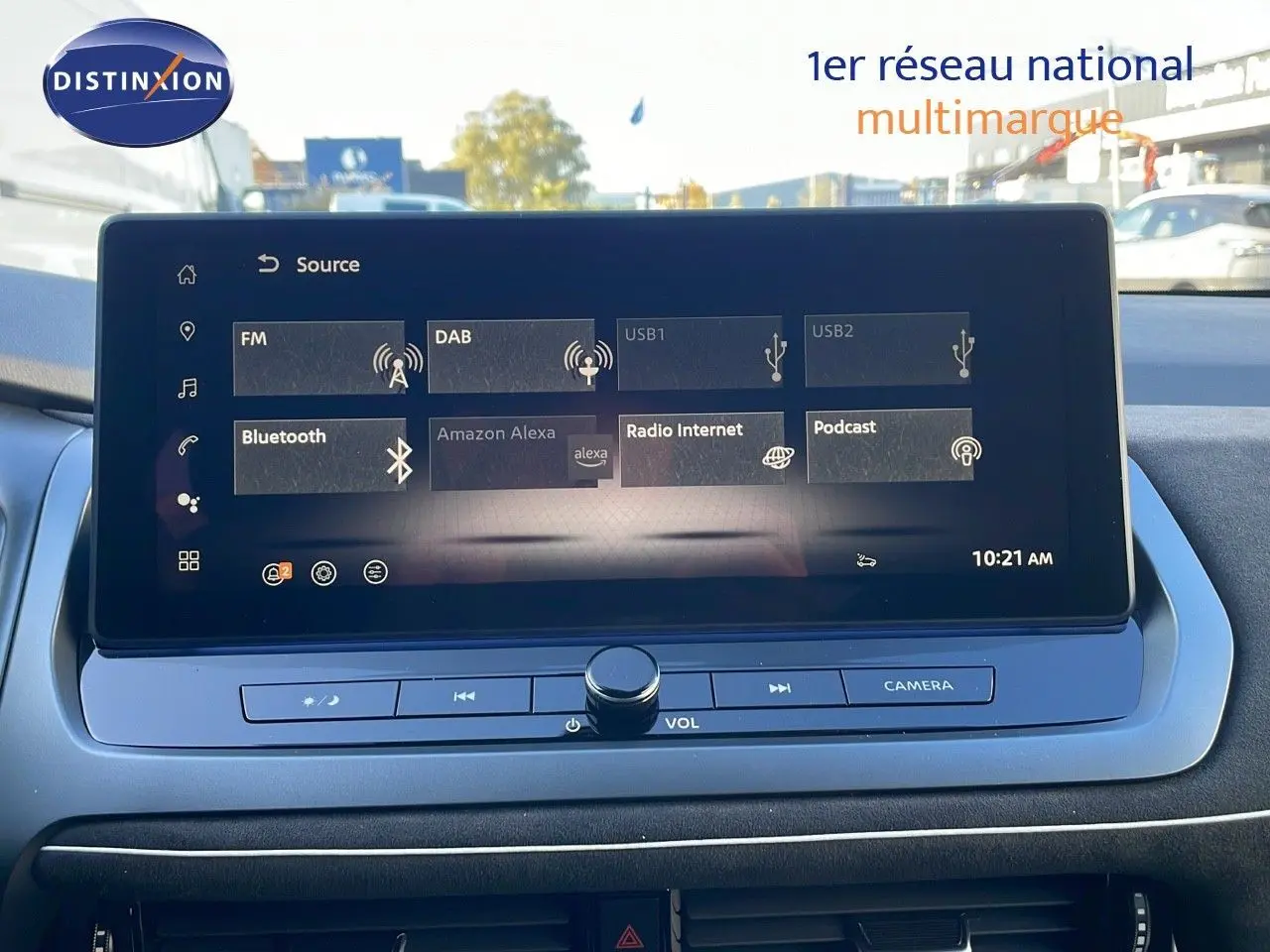 Écran tactile central du Nissan Qashqai 2025 blanc nacré, affichant les sources audio avec commandes de volume et caméra.