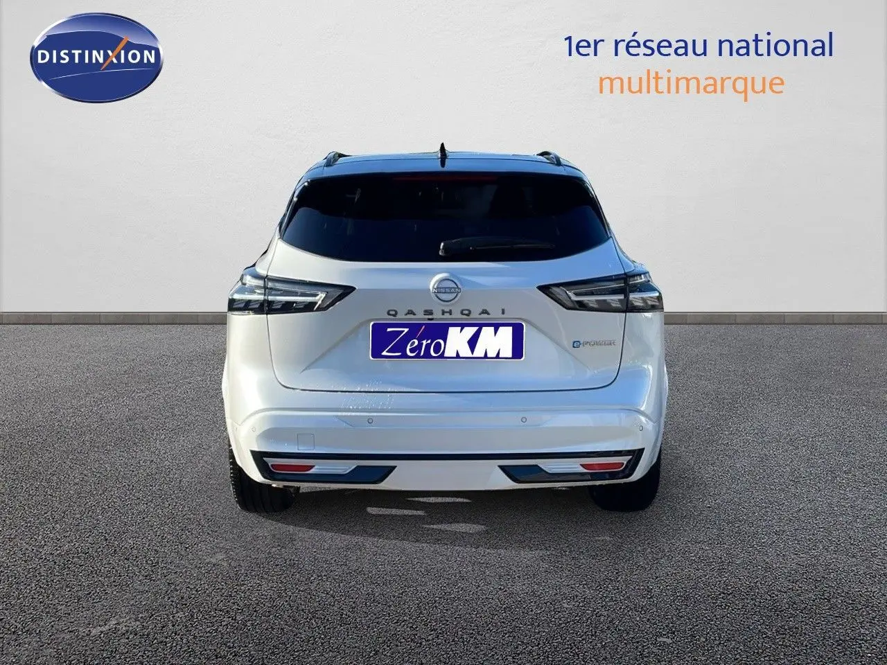 Vue arrière d'un Nissan Qashqai blanc nacré avec toit noir, modèle hybride 2025, affichant ses feux et logo distinctifs.