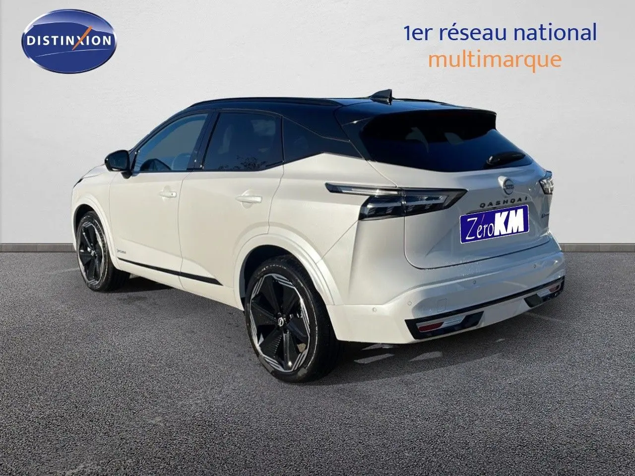 Nissan Qashqai blanc nacré avec toit noir, vue 3/4 arrière côté gauche, jantes noires et feux arrière LED.