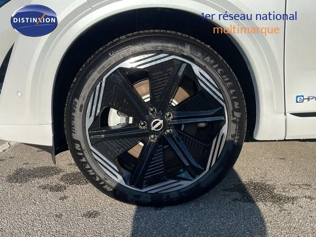 Gros plan sur la roue avant gauche du Nissan Qashqai blanc nacré avec jante noire et détails argentés.