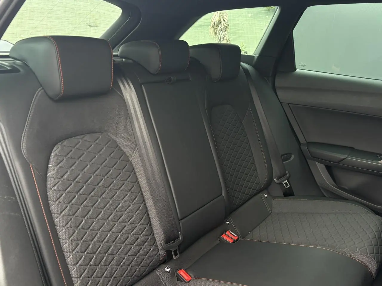 Vue latérale intérieure de la banquette arrière noire avec surpiqûres rouges du SEAT Leon 2025 version FR.