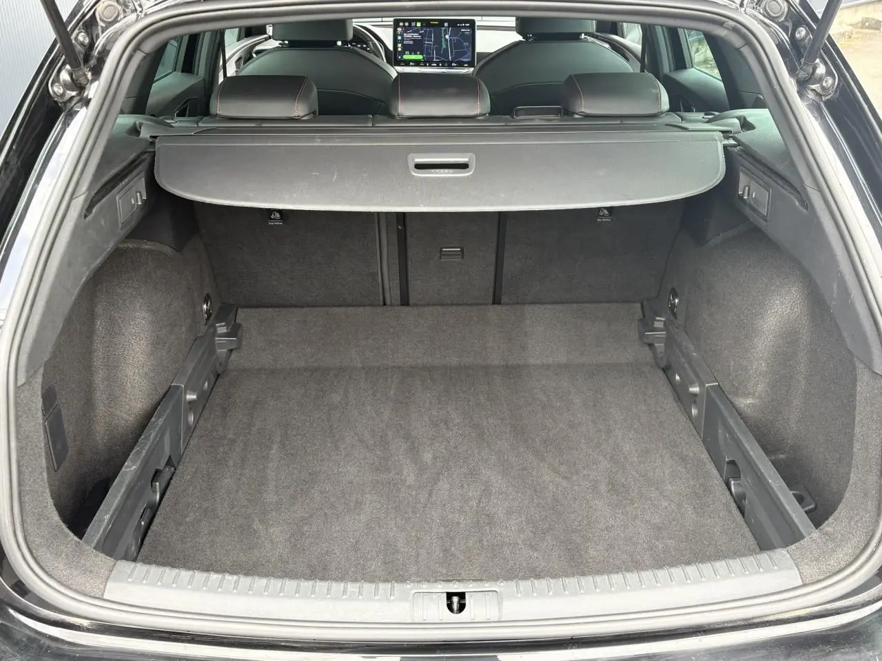 Coffre ouvert vu de l'arrière d'une SEAT Leon noir Minuit, montrant un espace de chargement propre et bien agencé.