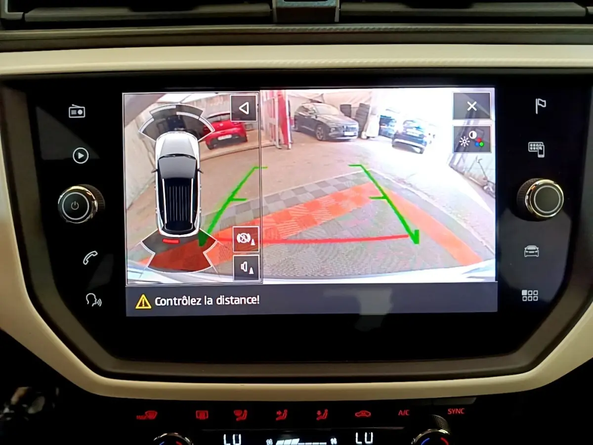 Écran tactile central montrant la caméra de recul et l’alerte de distance du SEAT Arona gris clair, vue intérieure.