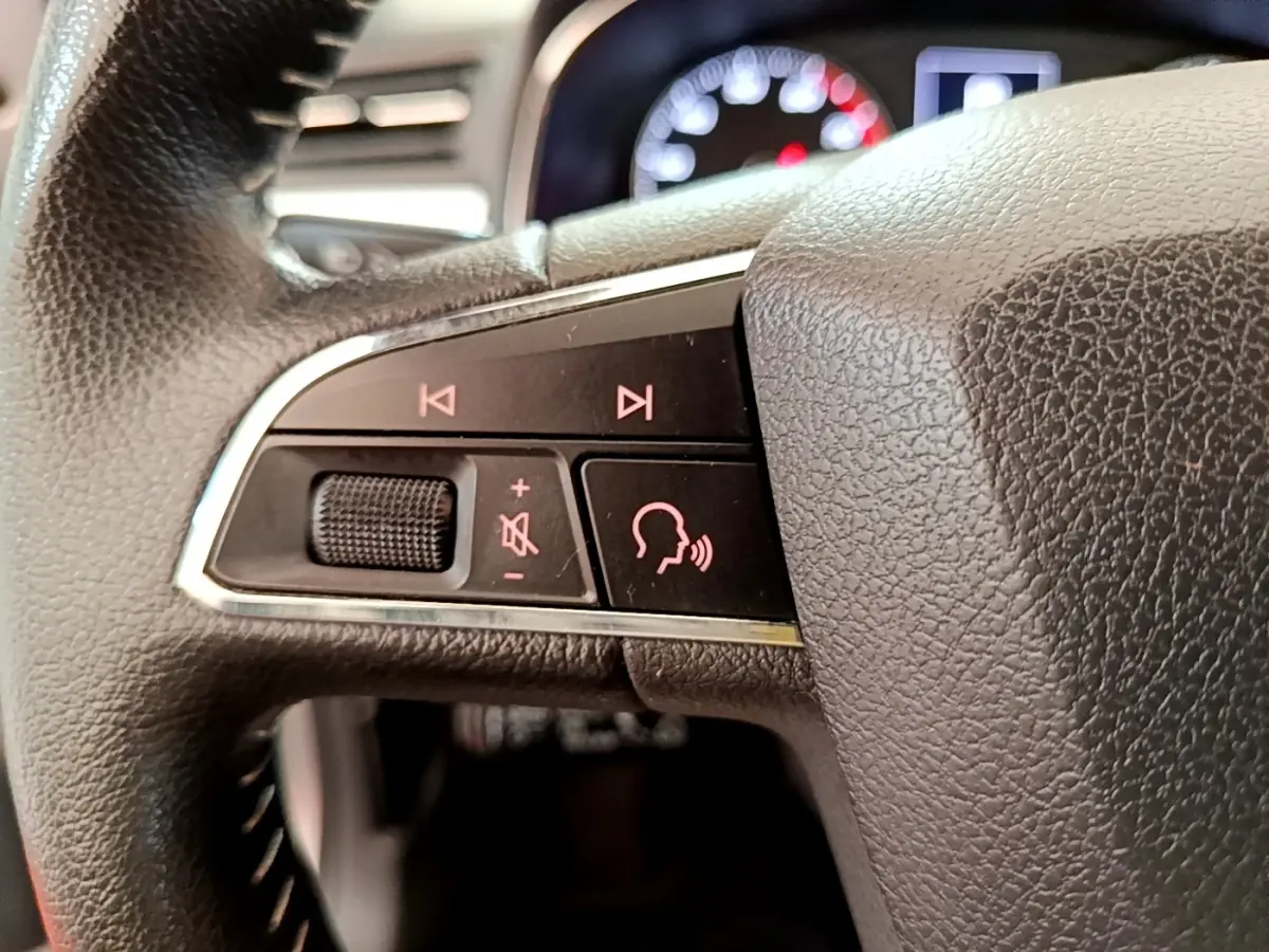 Gros plan sur le côté gauche du volant cuir et alu du SEAT Arona gris clair, avec commandes vocales et volume.