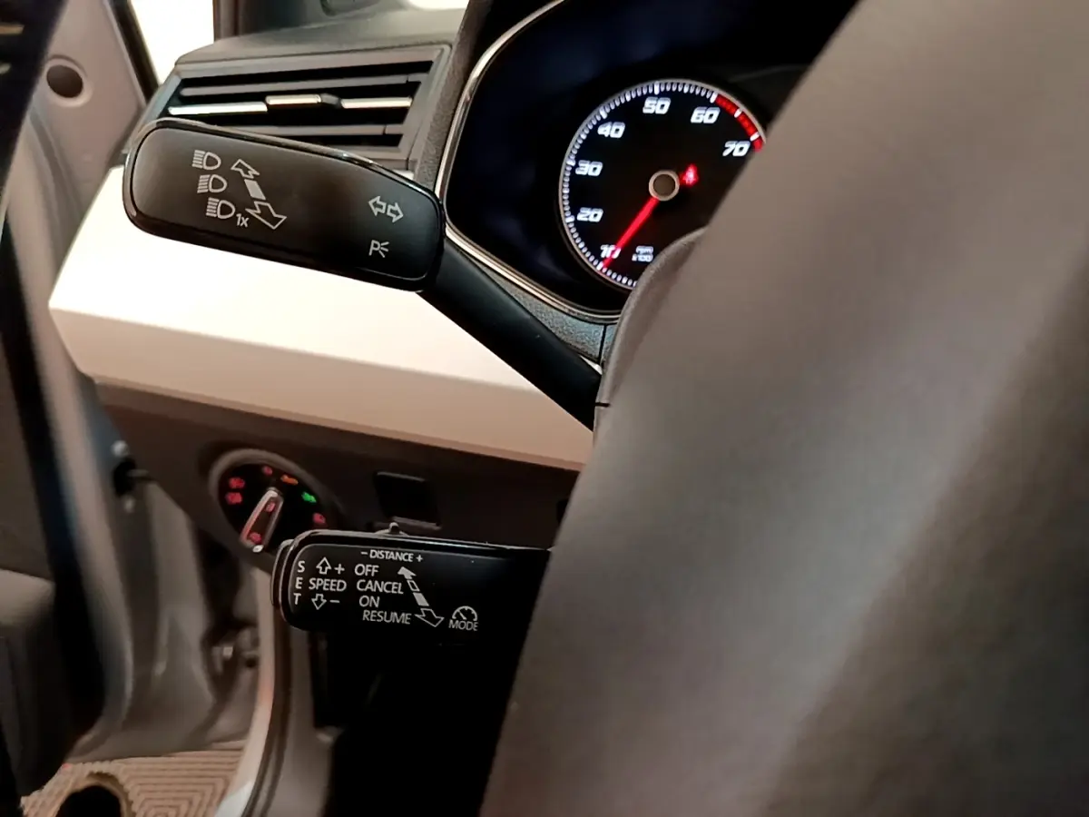 Gros plan sur le volant cuir et alu gris clair d’un SEAT Arona 2019, avec commandes au volant et tableau de bord éclairé.