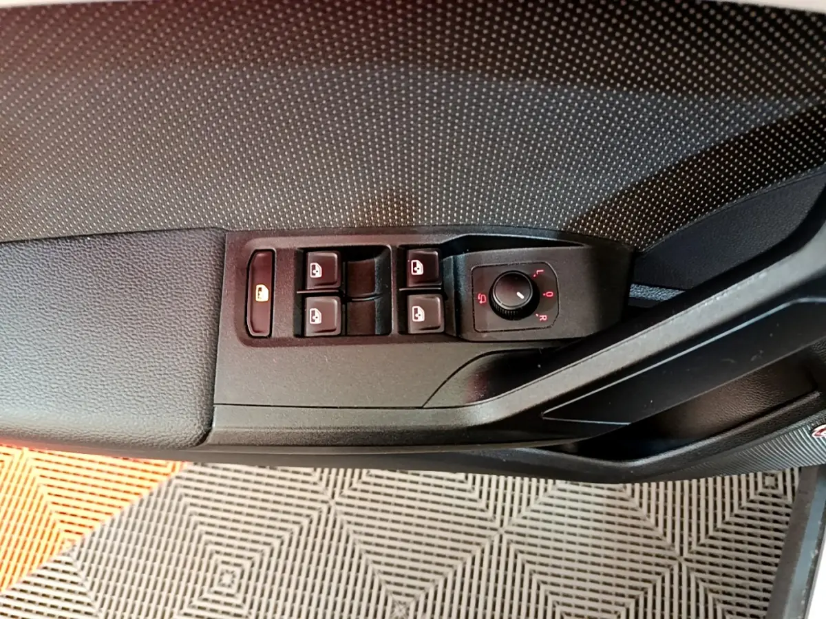 Gros plan sur la commande des vitres et rétroviseurs côté conducteur d'une SEAT Arona gris clair, intérieur noir.