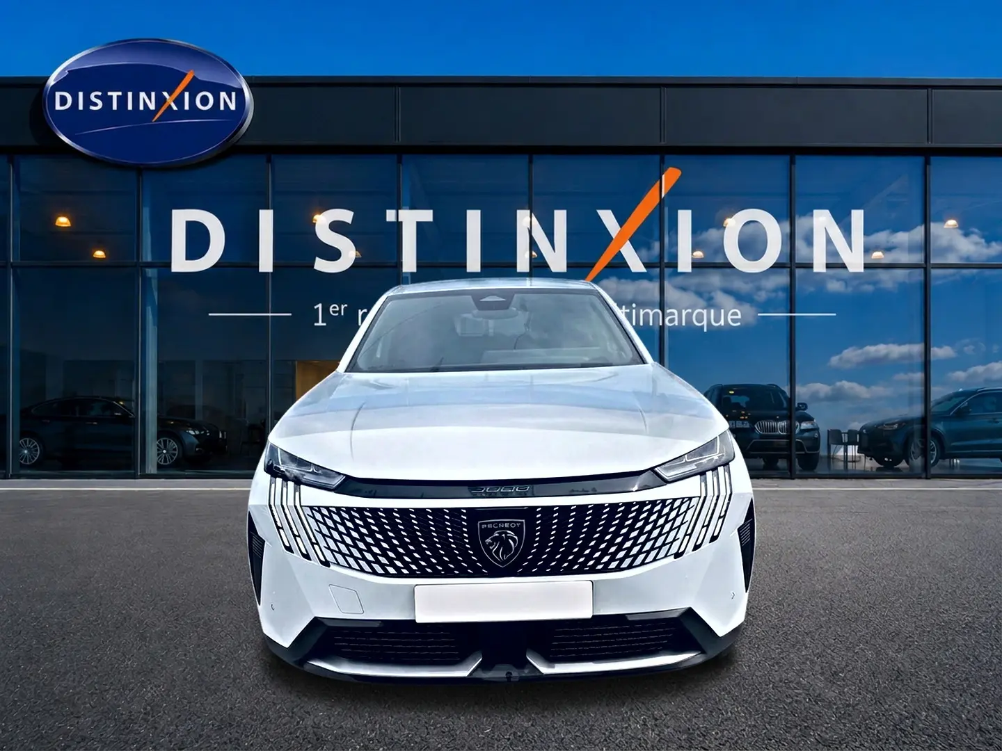 Vue frontale d'un Peugeot 3008 blanc 2025 avec calandre distinctive et phares LED fins, devant une vitrine Distinxion.