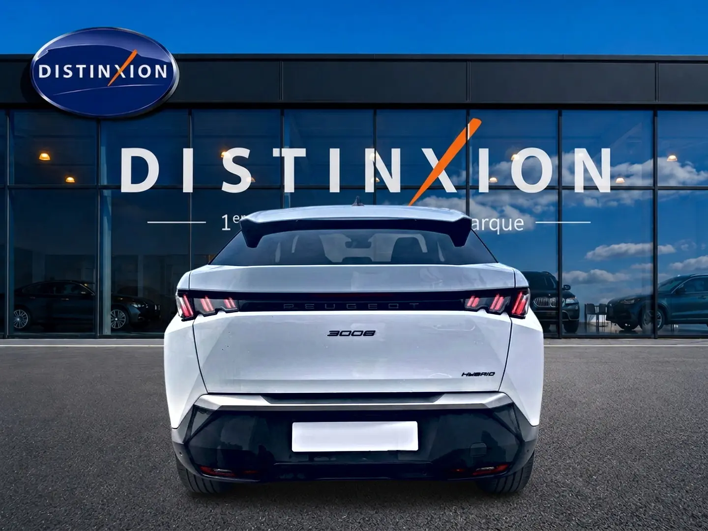 Vue arrière d'un Peugeot 3008 blanc hybride 2025, avec becquet arrière et feux LED distinctifs, devant une vitrine Distinxion.
