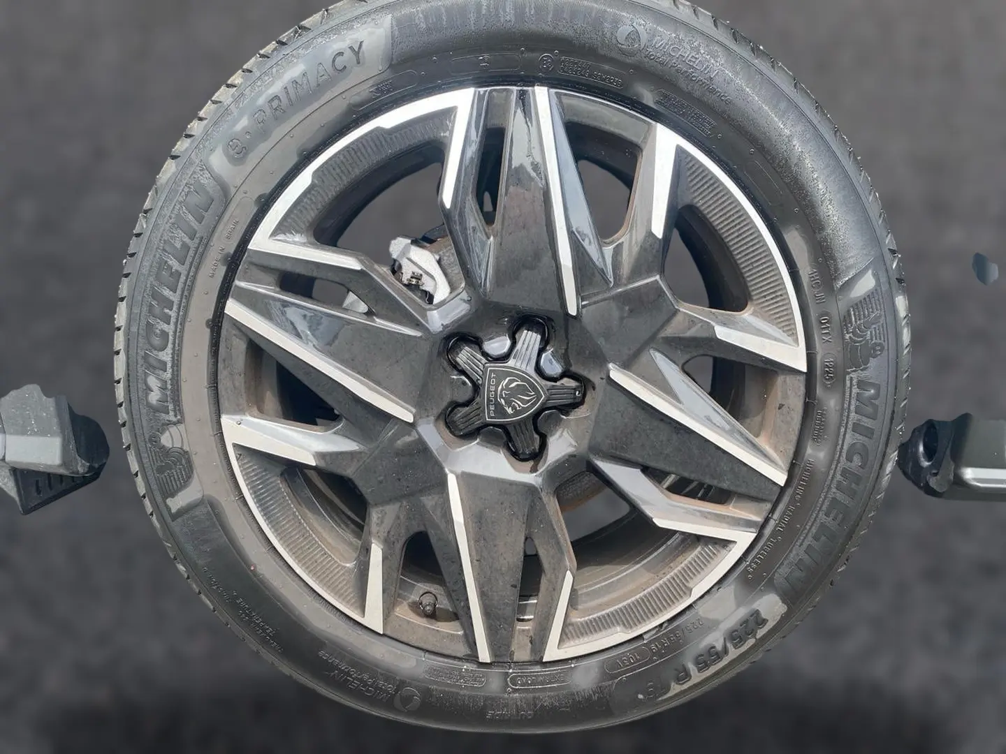 Gros plan sur la jante alu noire et argentée d’un Peugeot 3008 blanc, avec logo lion au centre.