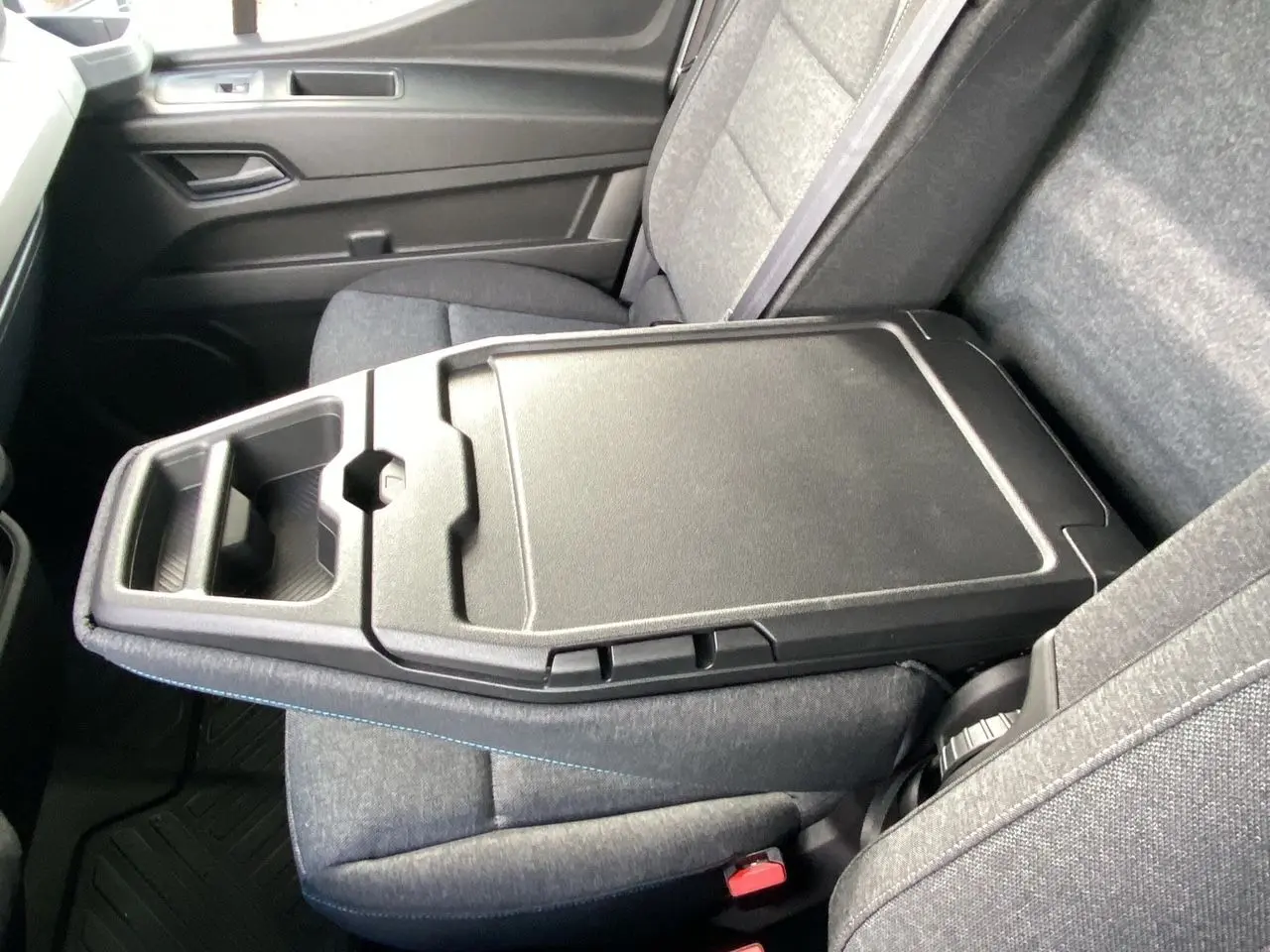 Vue rapprochée de l'accoudoir central noir et des sièges gris du Renault Master 2025, version utilitaire.