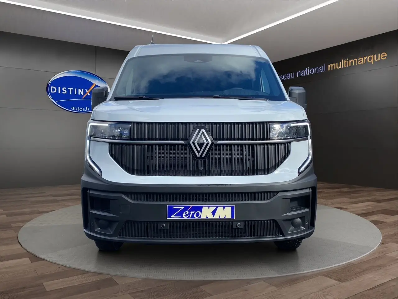 Vue avant d’un Renault Master blanc 2025 avec calandre noire et logo centré, sur fond intérieur showroom.