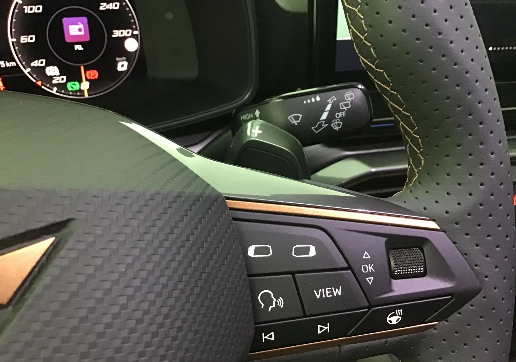 Gros plan sur le volant noir perforé de la CUPRA Leon 2023 avec commandes multifonctions et tableau de bord digital.
