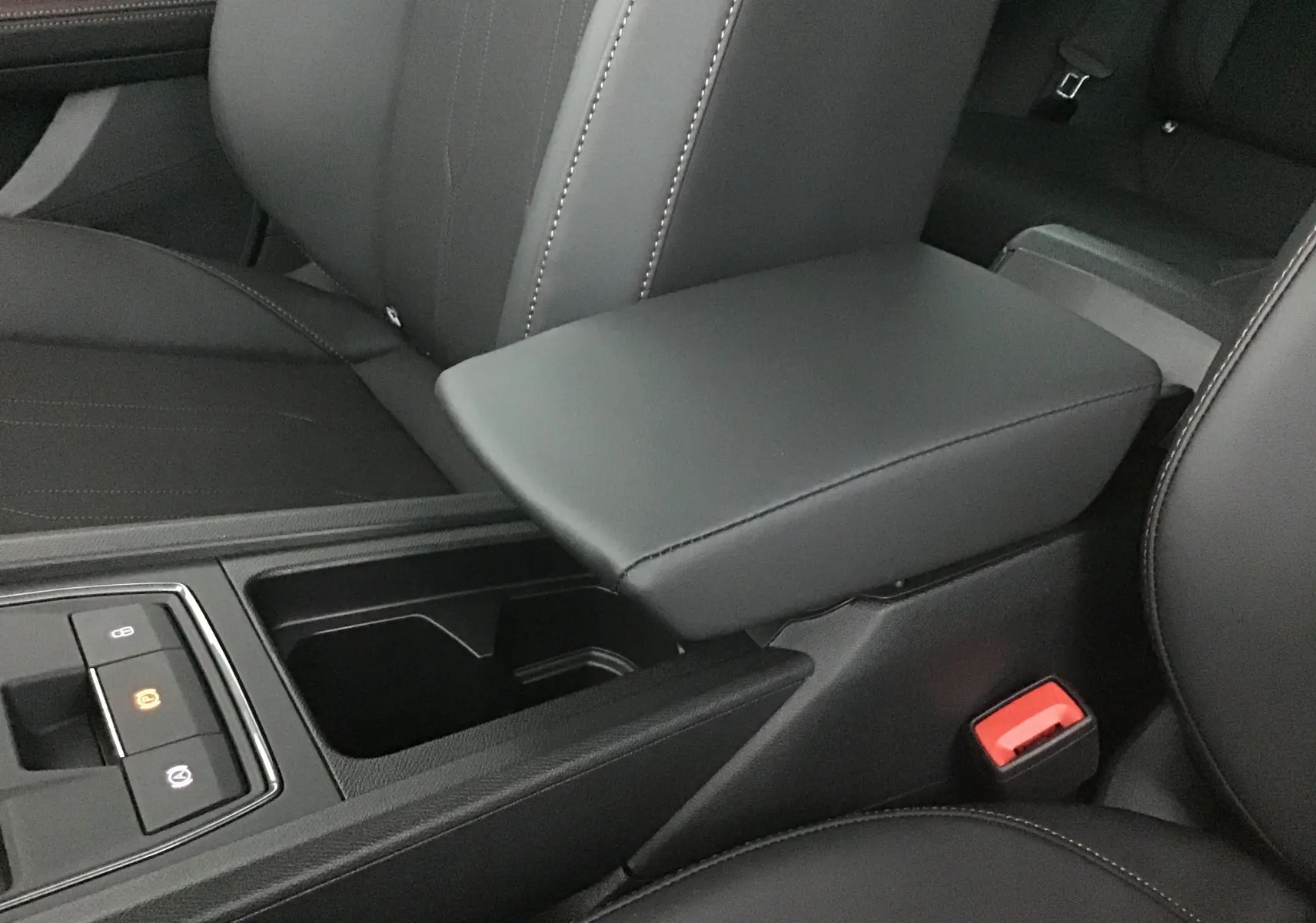Accoudoir central en cuir noir avec console et commandes électroniques dans l'habitacle du Cupra Leon 2023.