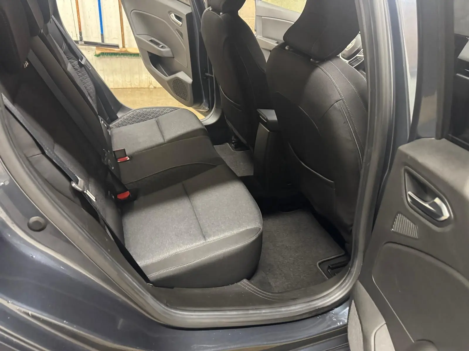 Vue intérieure côté arrière droit de la Renault Clio V Business 2019 gris titanium, montrant les sièges arrière et la porte ouverte.