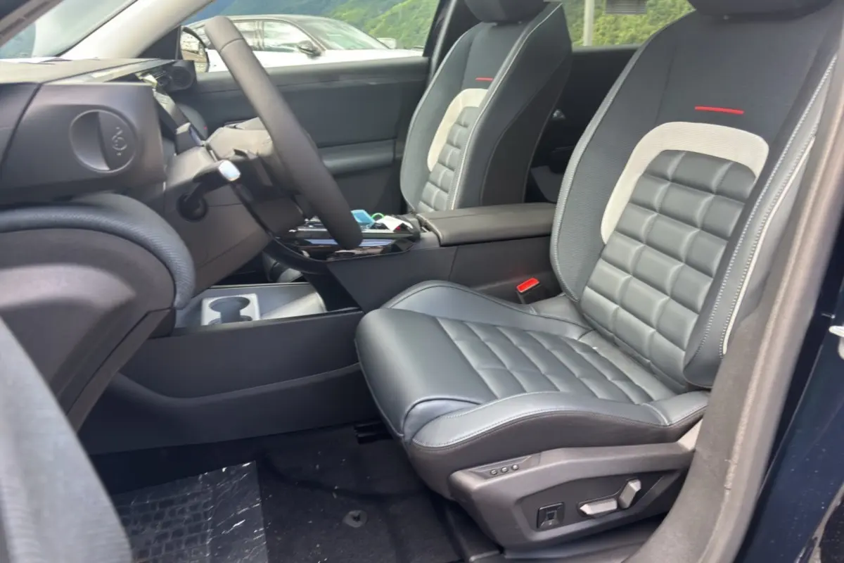Vue intérieure côté conducteur du Citroën C5 Aircross New Hybrid 2026, sièges cuir noir avec surpiqûres grises et accoudoir central.