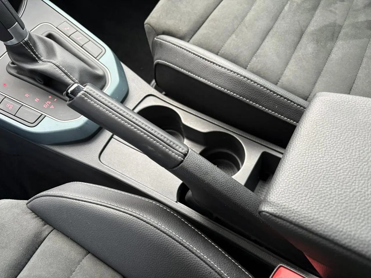 Gros plan intérieur sur la console centrale et frein à main du SEAT Arona TSI 115 DSG Xpérience, sièges gris.