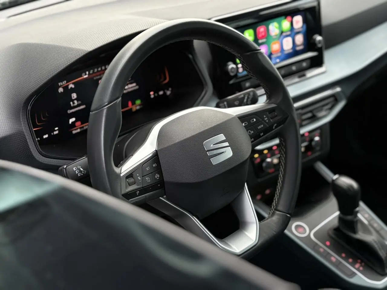 Vue rapprochée du volant multifonction noir et tableau de bord digital du SEAT Arona 2025, intérieur moderne.