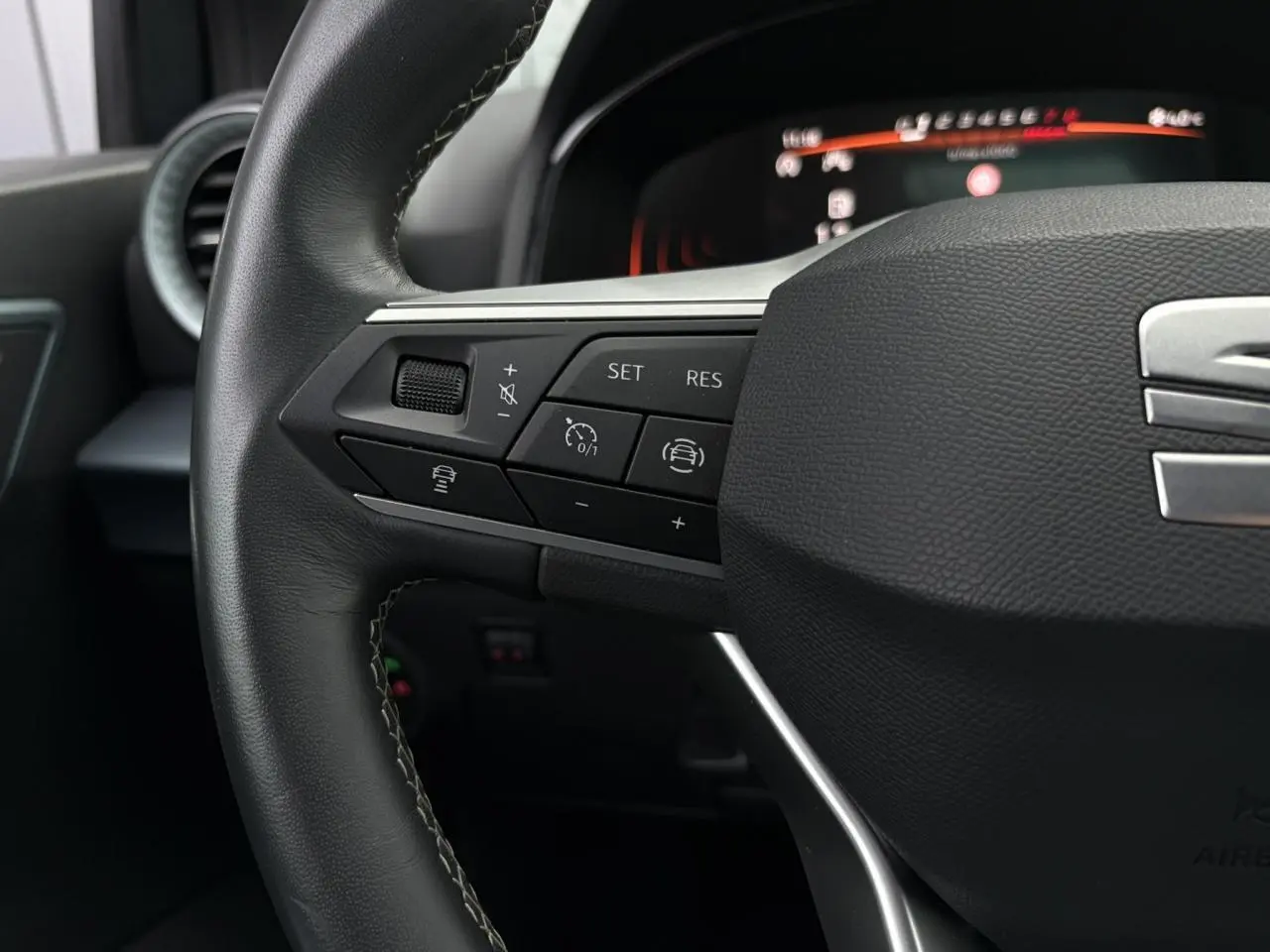 Gros plan sur le volant côté gauche du SEAT Arona 2025 avec commandes de régulateur de vitesse et assistance au maintien de voie.
