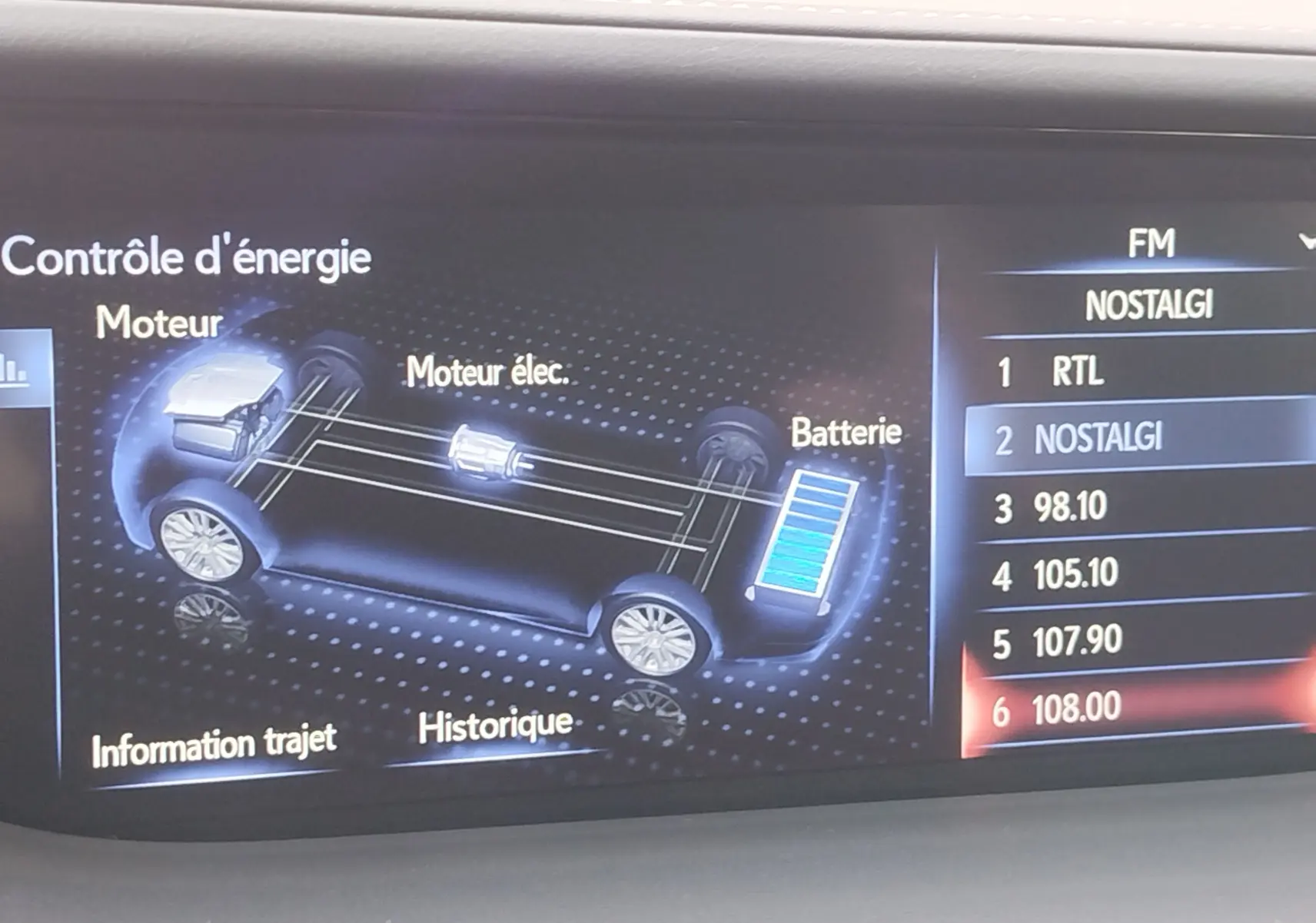 Écran intérieur du Lexus LS 500H montrant le contrôle d'énergie hybride et la liste des stations radio FM.