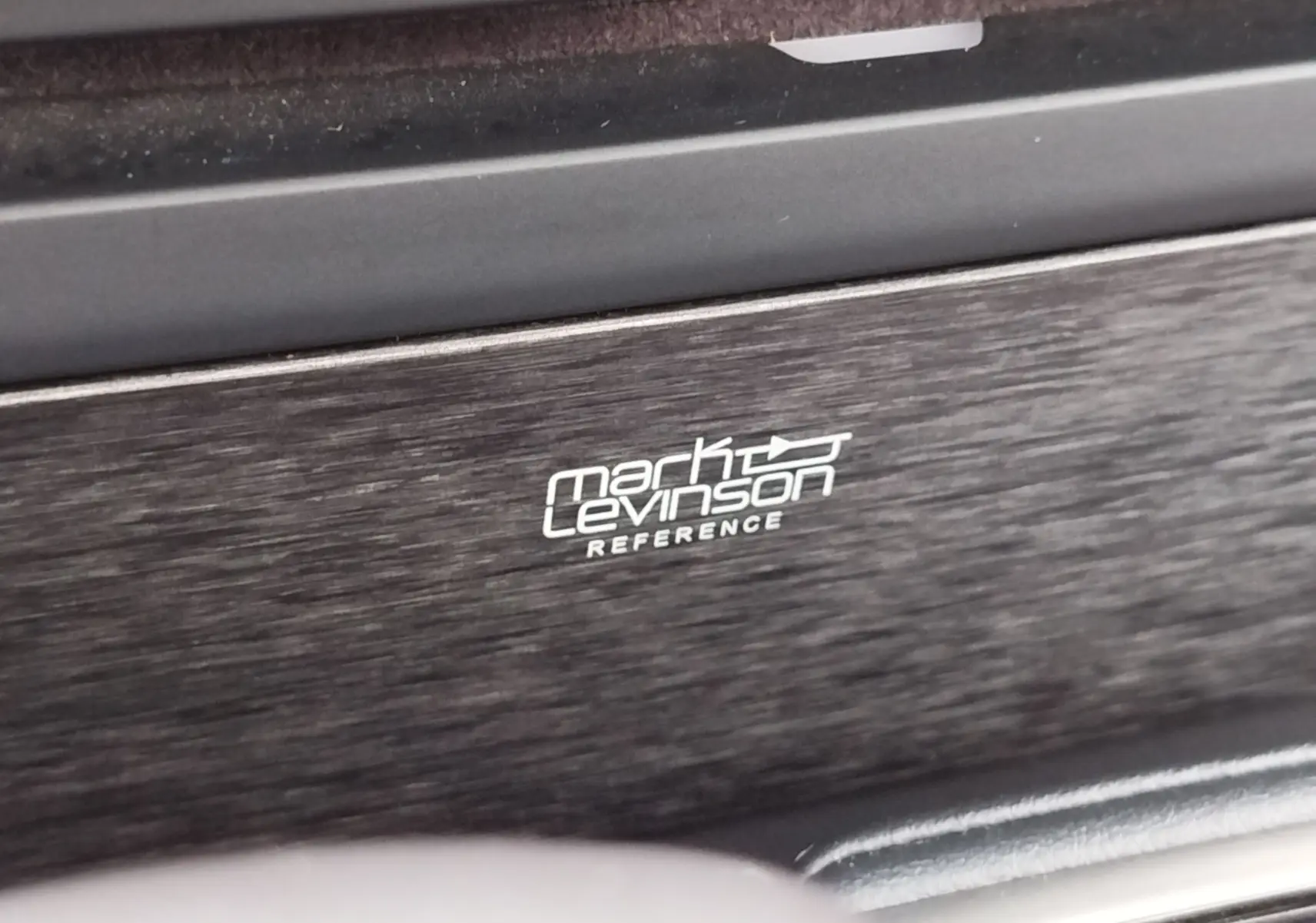 Gros plan sur le logo Mark Levinson sur la finition bois foncé de l’habitacle du Lexus LS 500H gris manganèse.