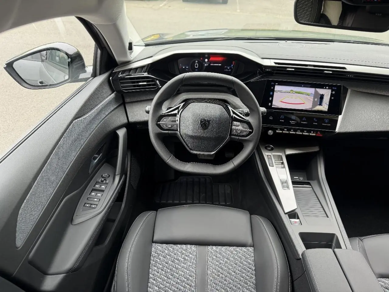 Intérieur de la Peugeot 308 2025 gris sellenium, vue centrée sur le volant et le tableau de bord digital avec écran tactile.