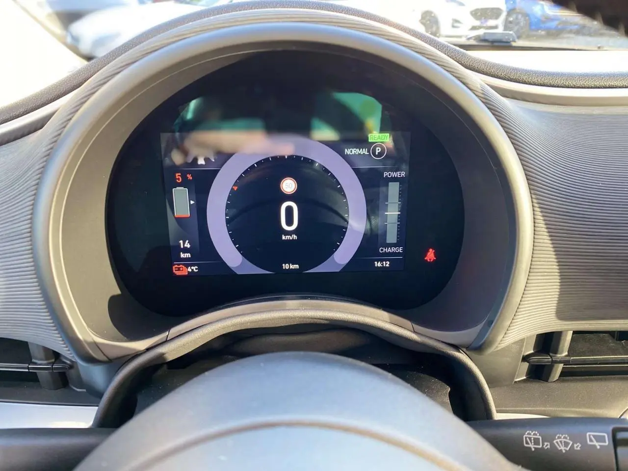 Vue rapprochée du tableau de bord numérique de la Fiat 500 électrique noire, affichant la vitesse et l'autonomie restante.