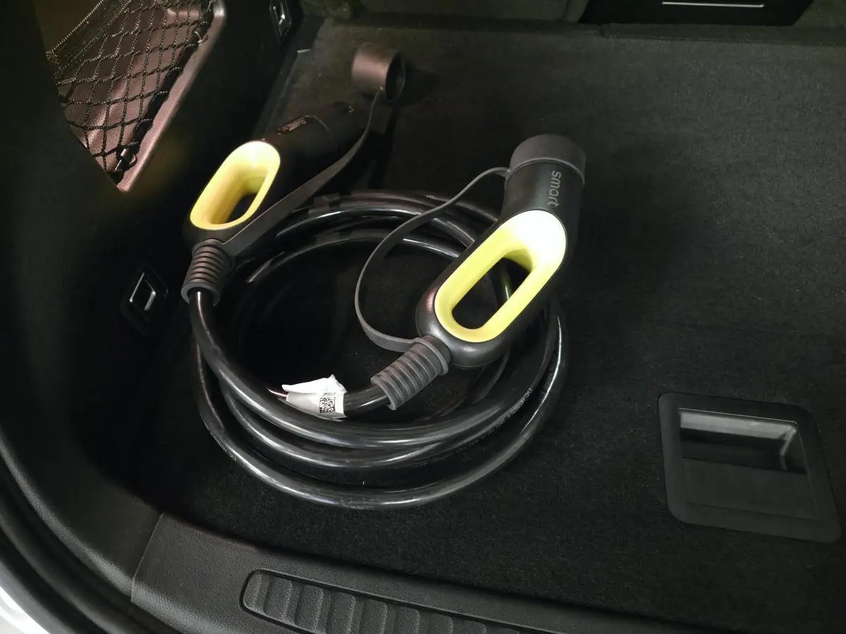 Câble de recharge électrique noir avec poignées jaunes dans le coffre d'une Smart #1 blanc 2024.
