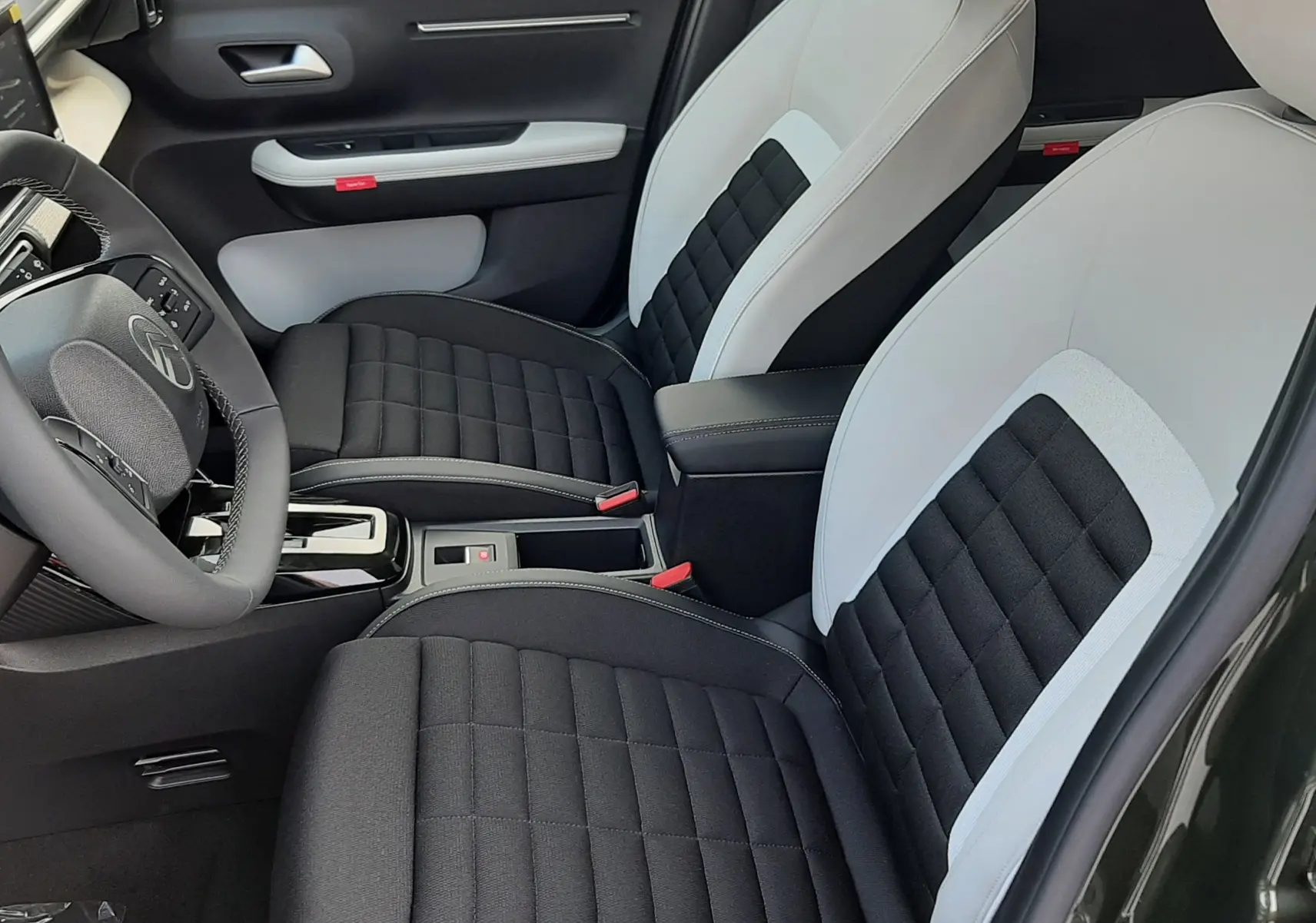 Vue intérieure côté conducteur du Citroën C3 Aircross hybride 2026, sièges bi-ton noir et blanc avec console centrale.