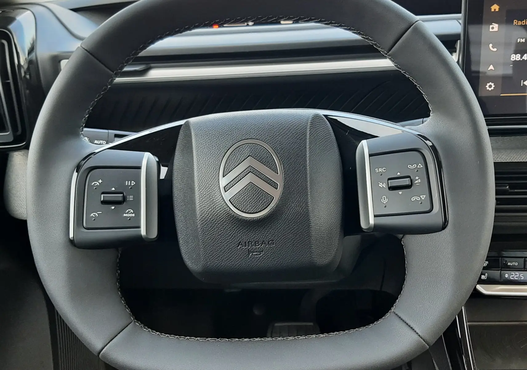 Vue rapprochée du volant cuir noir du Citroën C3 Aircross hybride 2026 avec commandes intégrées et tableau de bord visible.