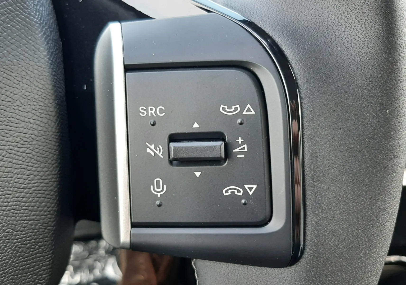 Gros plan sur les commandes multifonctions noires du volant côté gauche d’un Citroën C3 Aircross hybride 2026.