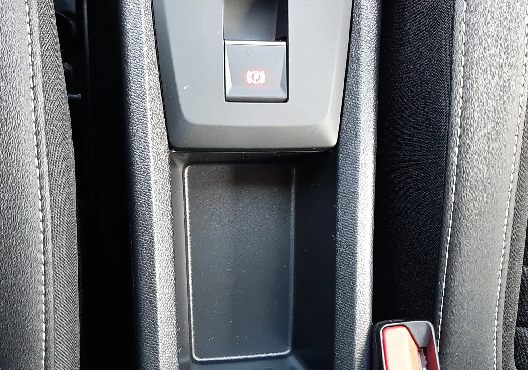 Gros plan sur la console centrale noire avec frein à main électrique et bouton de verrouillage dans une Citroën C3 Aircross hybride.