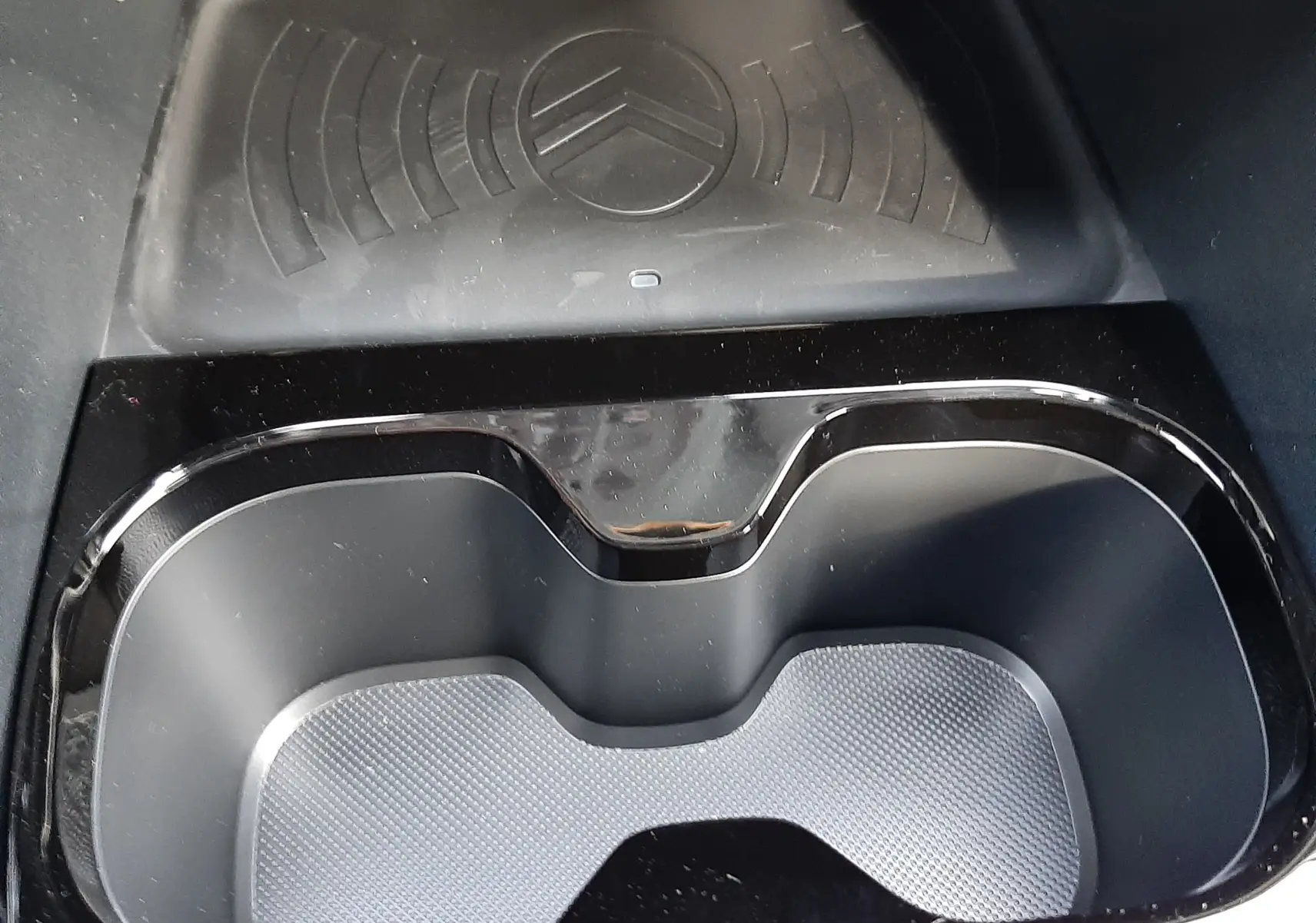 Gros plan sur le porte-gobelets noir et le chargeur à induction avec logo Citroën dans l’habitacle du C3 Aircross hybride 2026.