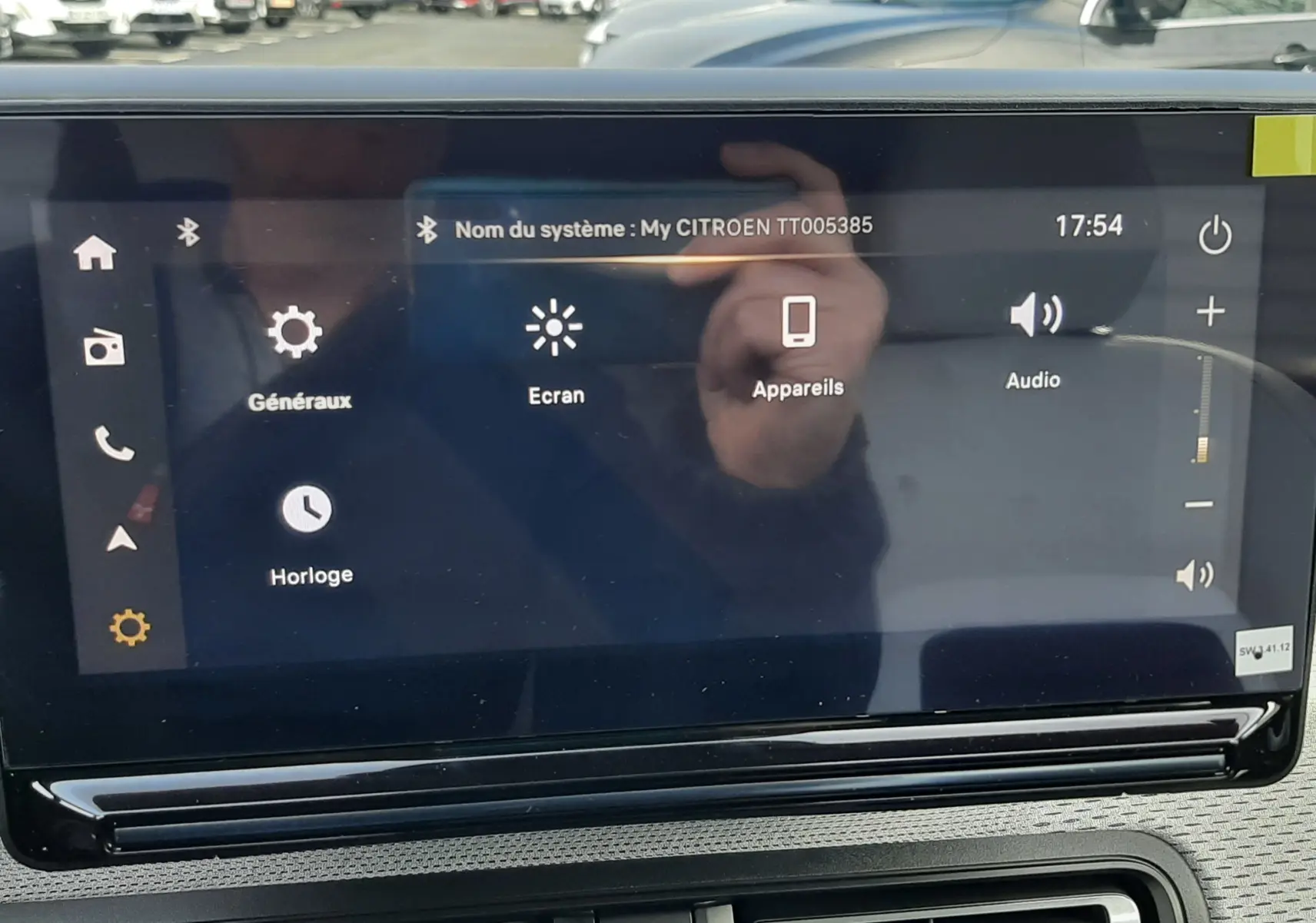 Écran tactile central du tableau de bord d'une Citroën C3 Aircross hybride 2026, avec commandes visibles et reflet extérieur.