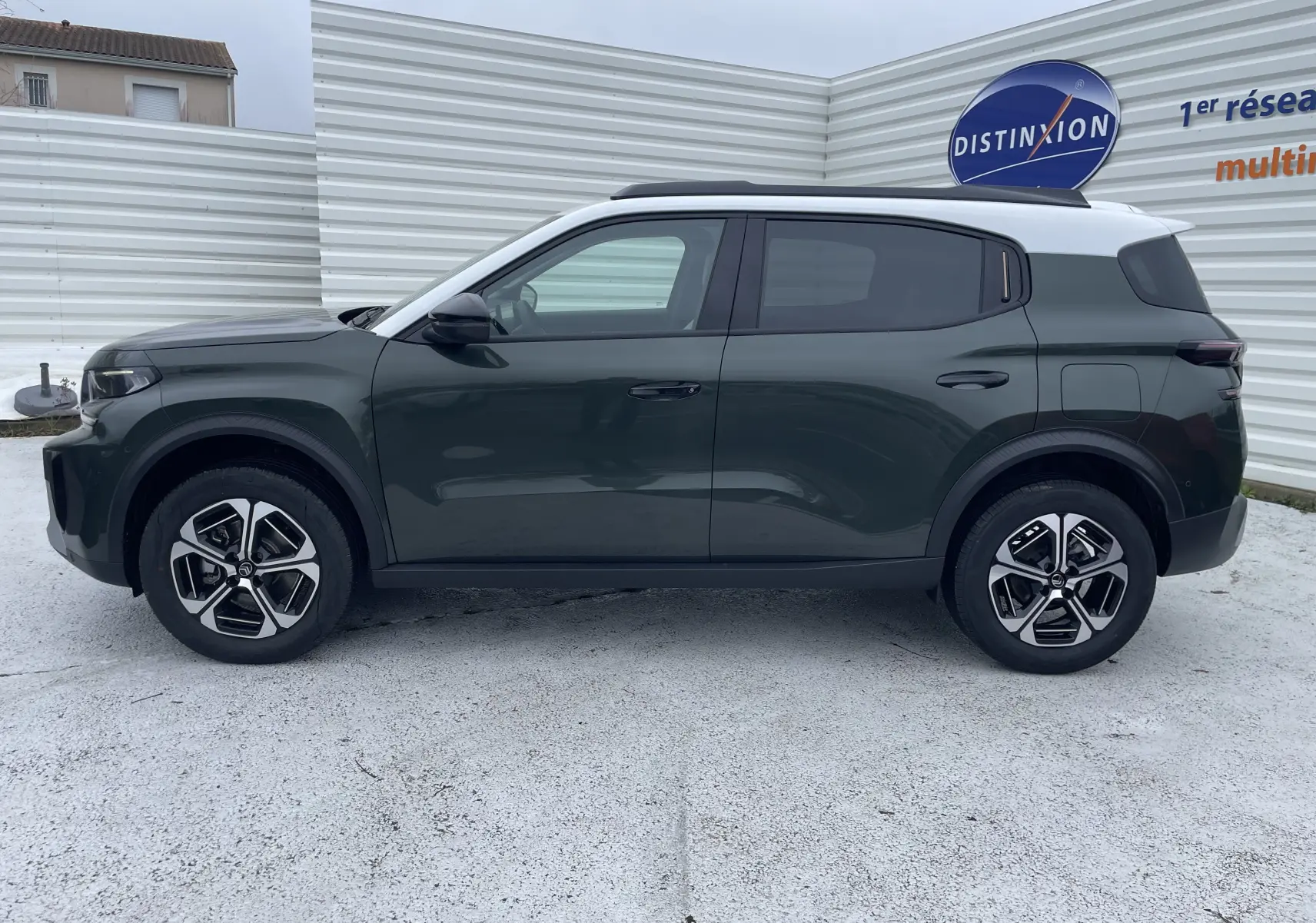 Vue de profil côté gauche d'une Citroën C3 Aircross hybride 2026 vert Montana avec toit blanc opale et jantes bicolores.