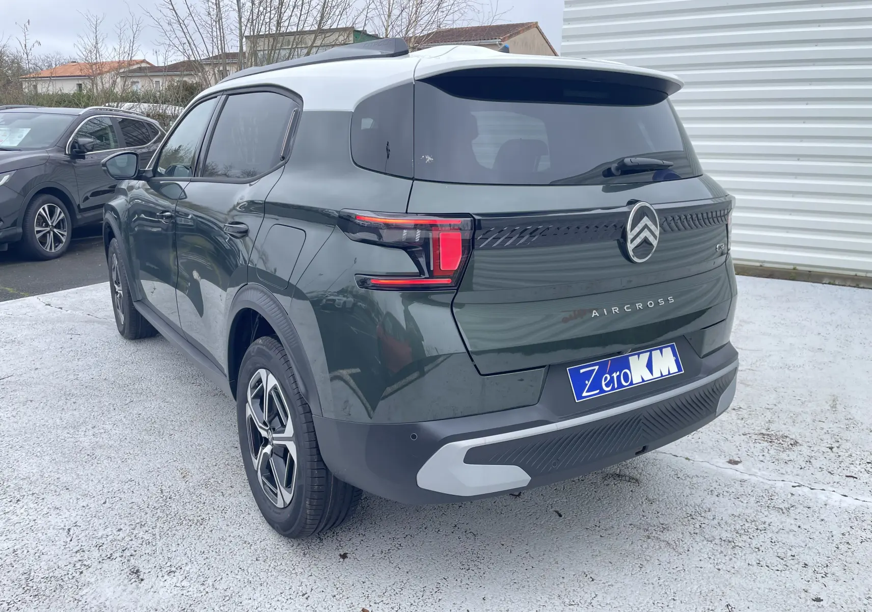 Vue 3/4 arrière droite d'un Citroën C3 Aircross hybride 2026 vert Montana avec toit blanc opale et détails noirs.