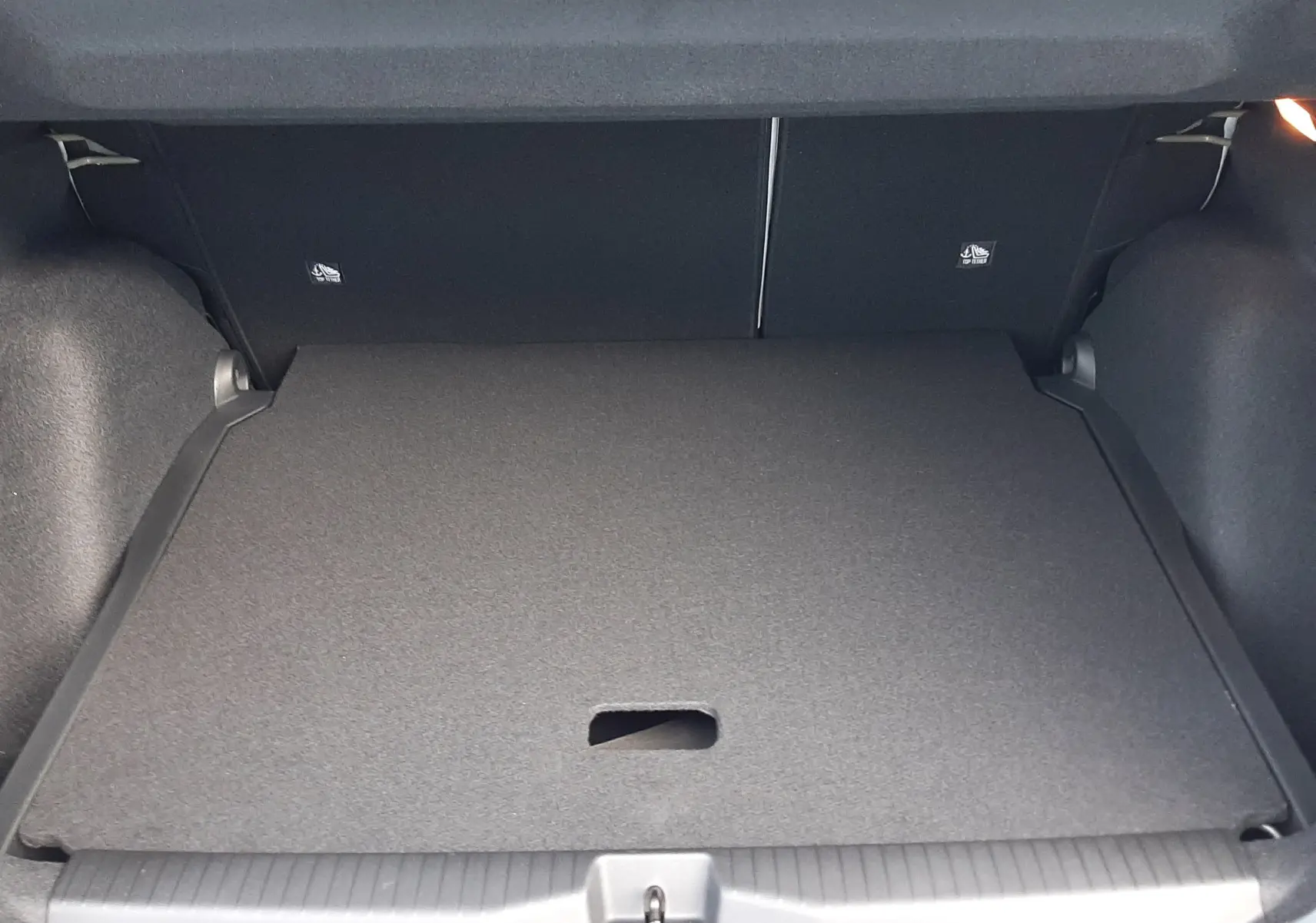 Vue du coffre ouvert du Citroën C3 Aircross hybride 2026 vert Montana, montrant le plancher plat et l'intérieur noir.