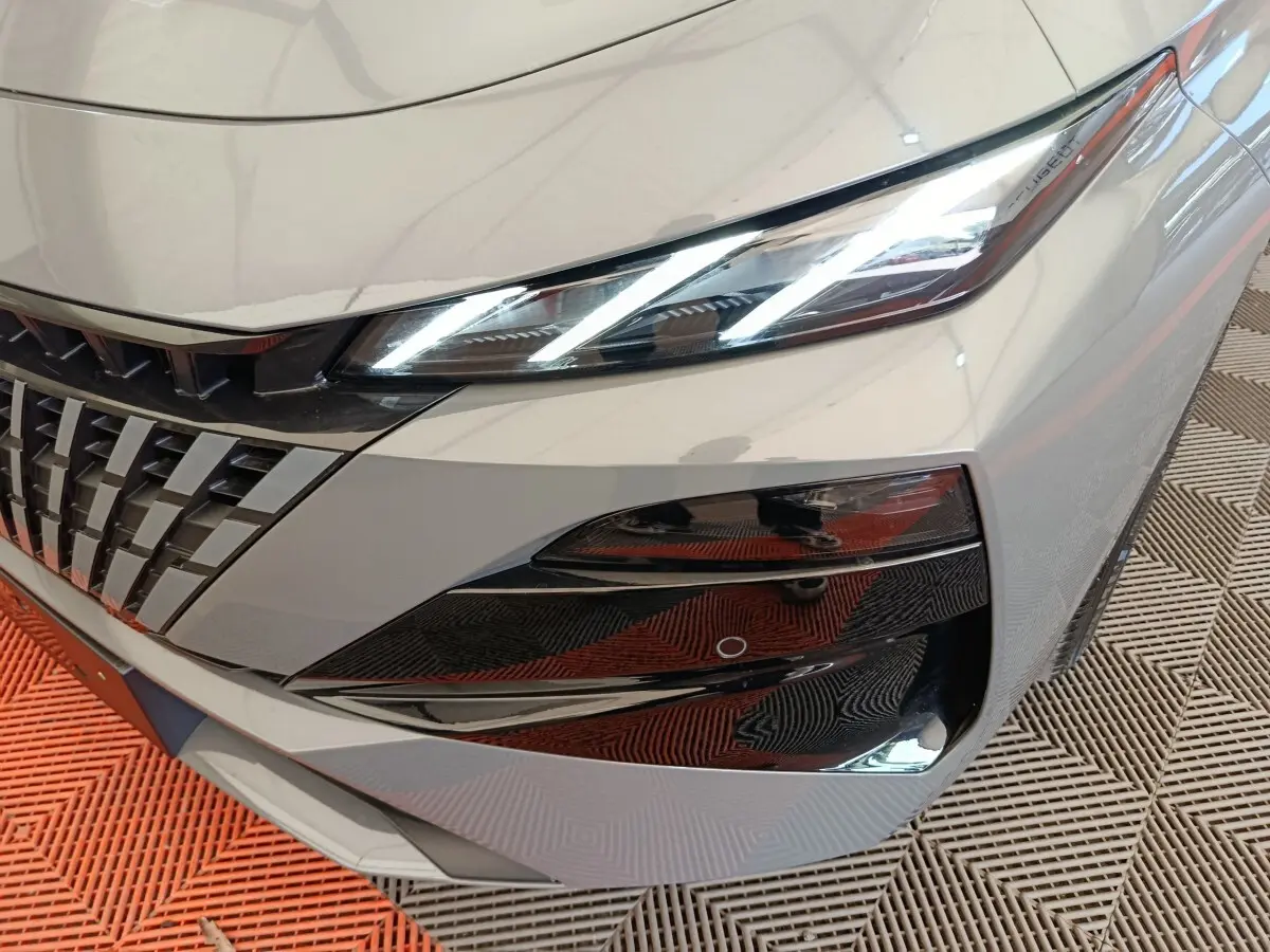 Gros plan sur l'avant droit gris foncé de la Peugeot 308 2026, mettant en valeur le phare LED et la calandre distinctive.