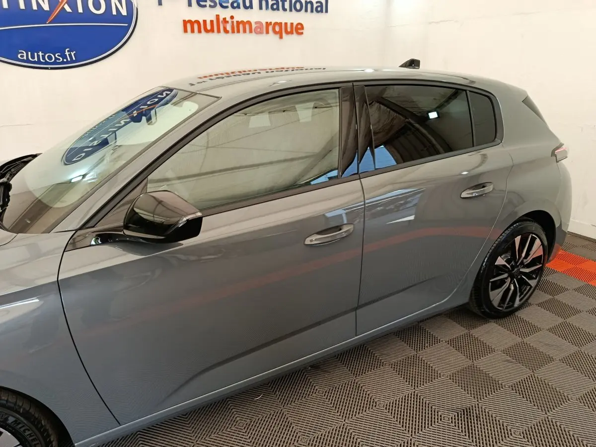 Vue de profil côté gauche d'une Peugeot 308 gris foncé 2026 avec jantes alliage et rétroviseurs noirs.