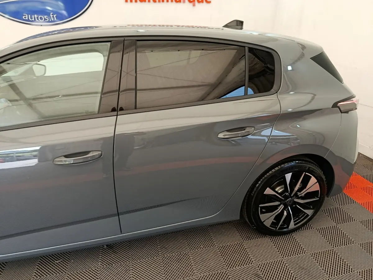 Vue latérale droite d'une Peugeot 308 gris foncé, mettant en valeur les jantes alliage et les vitres teintées.