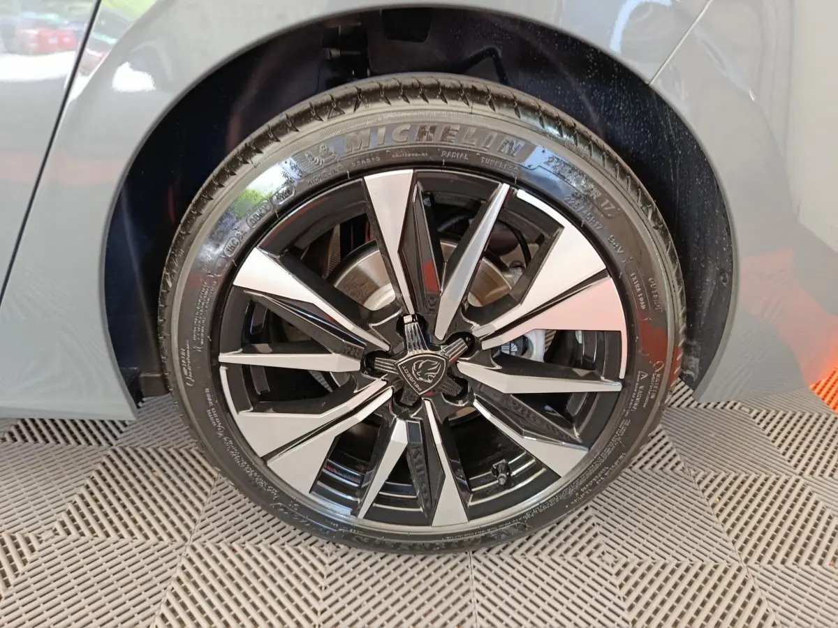 Gros plan sur la roue avant droite d’une Peugeot 308 gris foncé, avec jante alliage noire et argentée au design moderne.