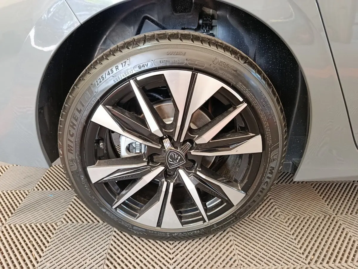Gros plan sur la roue avant droite avec jante alliage bicolore de la Peugeot 308 gris foncé 2026.