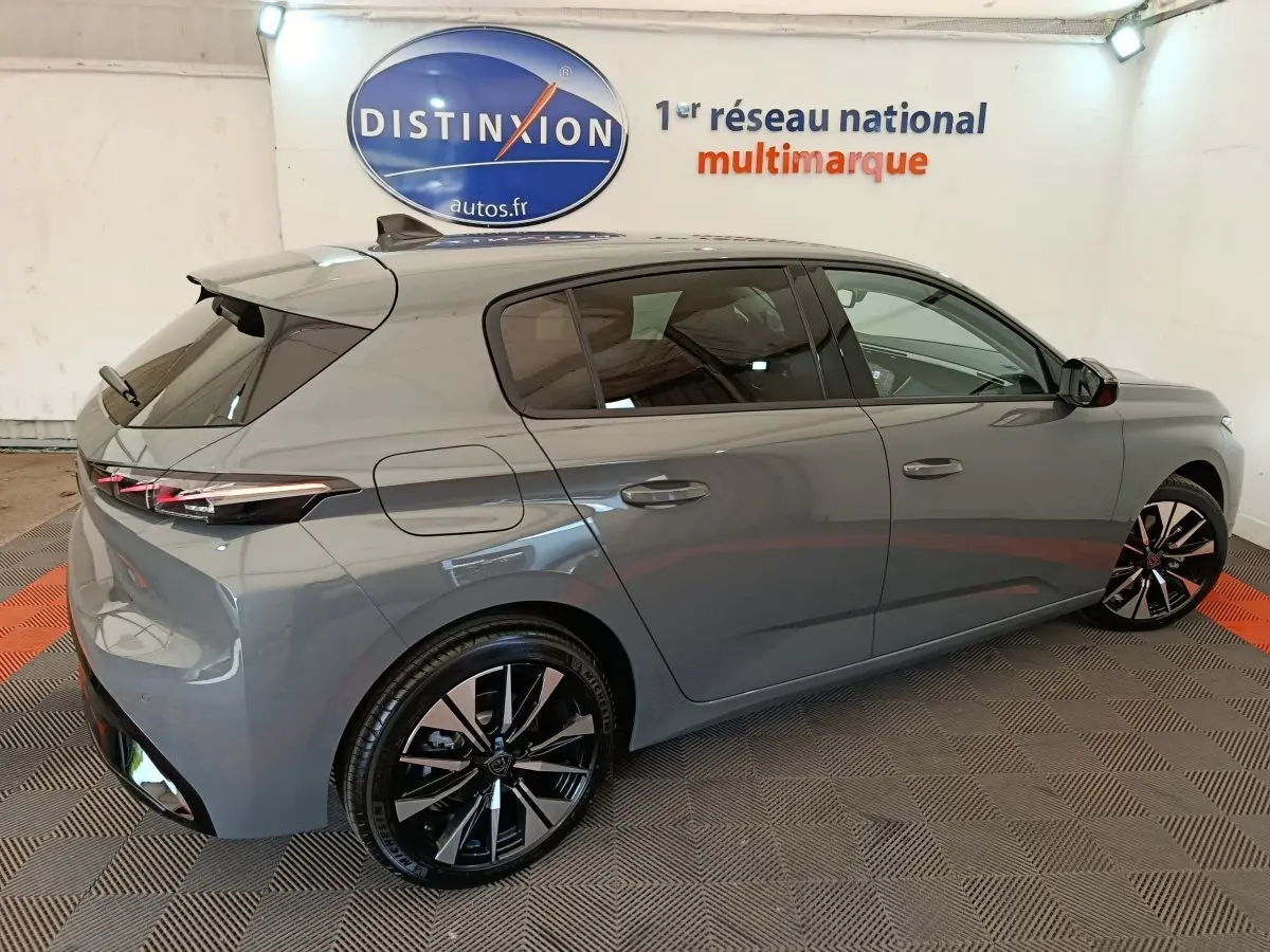 Peugeot 308 BlueHDi 130 en gris foncé vue 3/4 arrière droit, avec jantes noires et feux arrière LED fins.