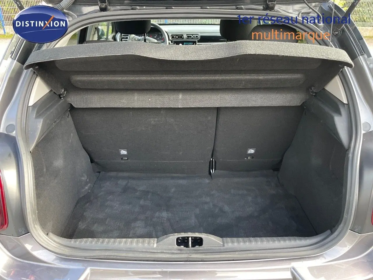 Coffre ouvert d'une Citroën C3 gris platinium métal, vue arrière montrant l'espace de chargement et l'intérieur du véhicule.