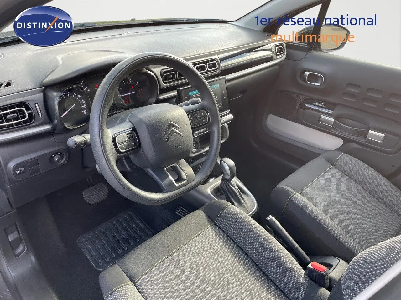 Intérieur avant d'une Citroën C3 2023, vue côté conducteur, volant multifonction et sellerie tissu gris noir.