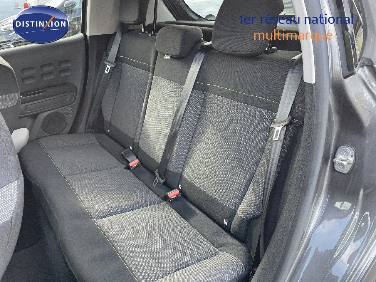 Vue intérieure côté gauche des sièges arrière en tissu gris noir d'une Citroën C3 gris platinium 2023 avec ceintures de sécurité visibles.